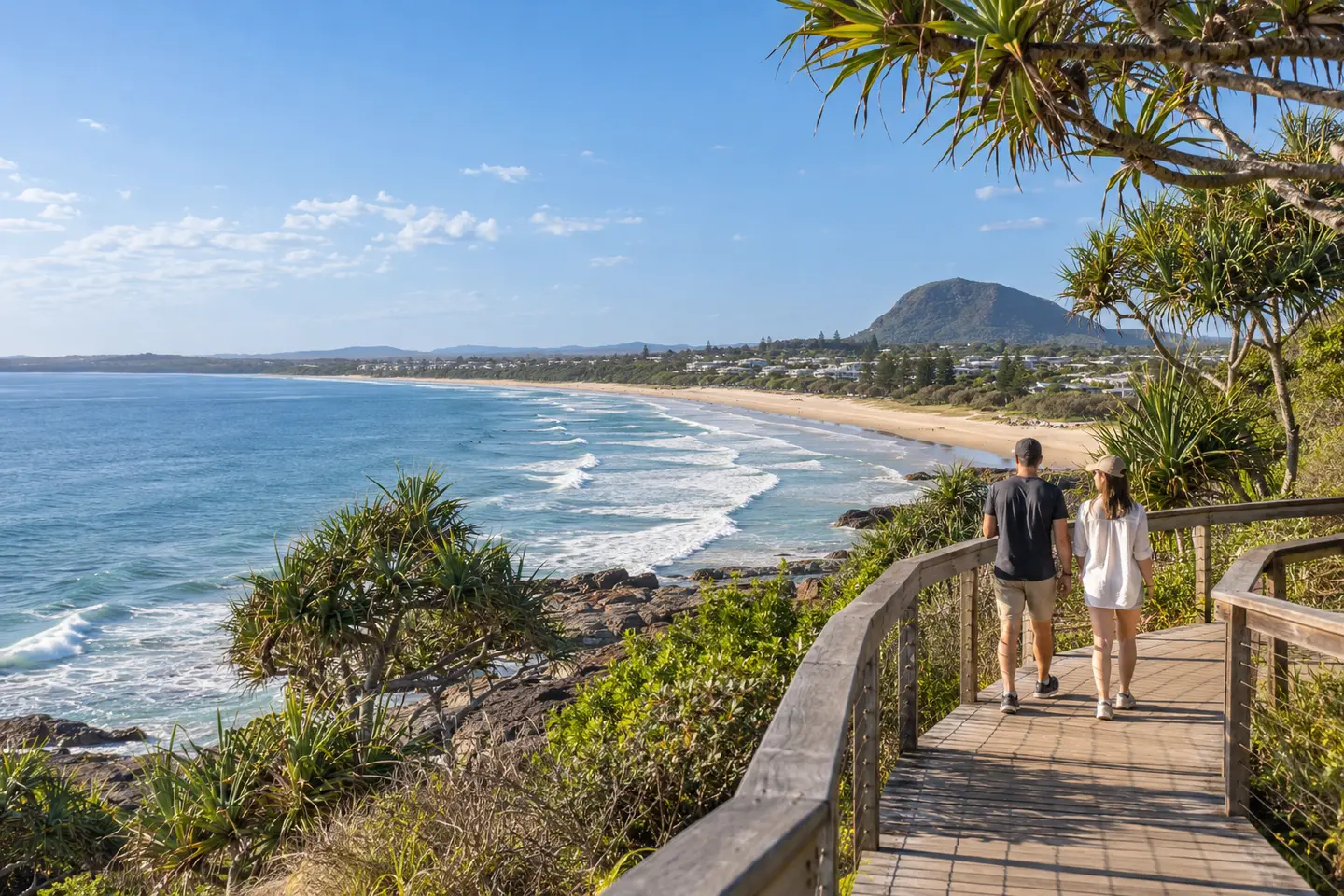 Couple walking along the Coolum coastal boardwalk above the beach